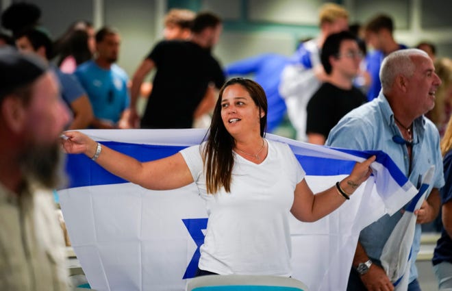 Revitil Chkoury drapes an Israeli flag around her during a unity gathering for Israel at Florida Gulf Coast University's Seidler Hall in Fort Myers, Fla., in October.