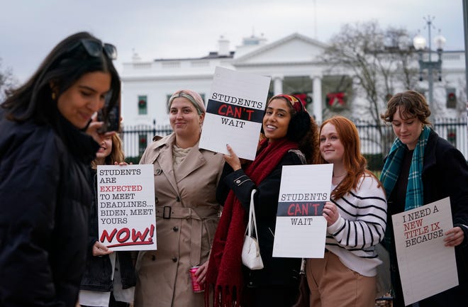 A group of Title IX reform advocates holds up signs saying 'students can't wait' during a protest outside the White House on Tuesday.