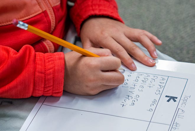 Keylin Perez writes down what she learns as students study apples by reading a non-fiction book at Jeremiah Gray Elementary School, Tuesday, Oct. 10, 2023 during Fall break intercession classes. Perry Township school district has a 2-week break with the classes which help kids catch up on classwork during the break.