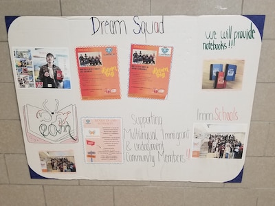 A high school student's poster affixed to a white brick wall.