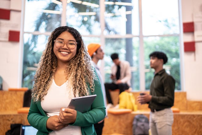 Portrait of a young student woman holding a digital tablet at university.