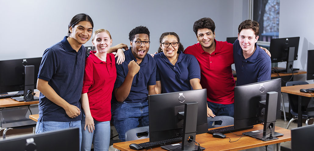 Teens in a computer lab wearing red and blue shirts