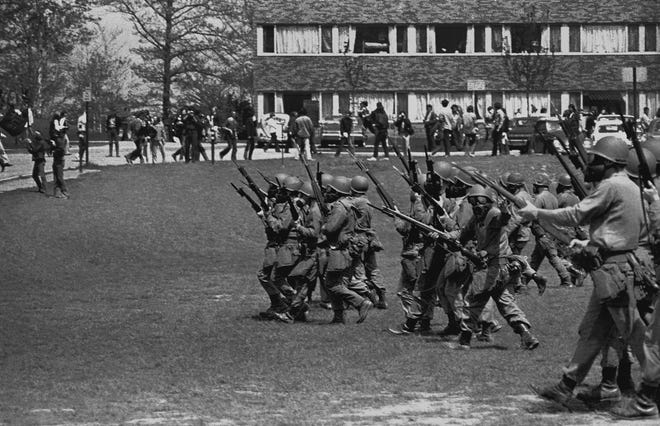 Ohio National Guardsmen head back toward Taylor Hall and the Pagoda after stopping on a practice field near the Prentice Hall parking lot on May 4, 1970 in Kent, Ohio.