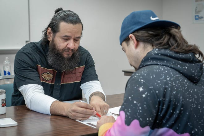 Math professor Michael Lopez helps a student work through an algorithm for calculating ladder rung placement in his math for welders class.