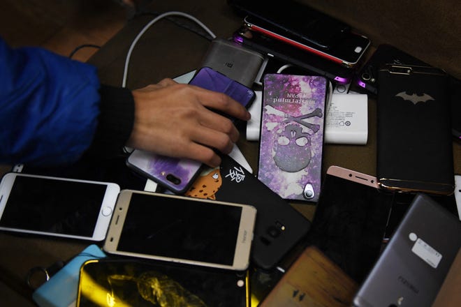 A student picks up his mobile phone after sitting an exam at a technical school in Jinan, in China's eastern Shandong province on January 29, 2018. (Photo by GREG BAKER / AFP) (Photo by GREG BAKER/AFP via Getty Images)